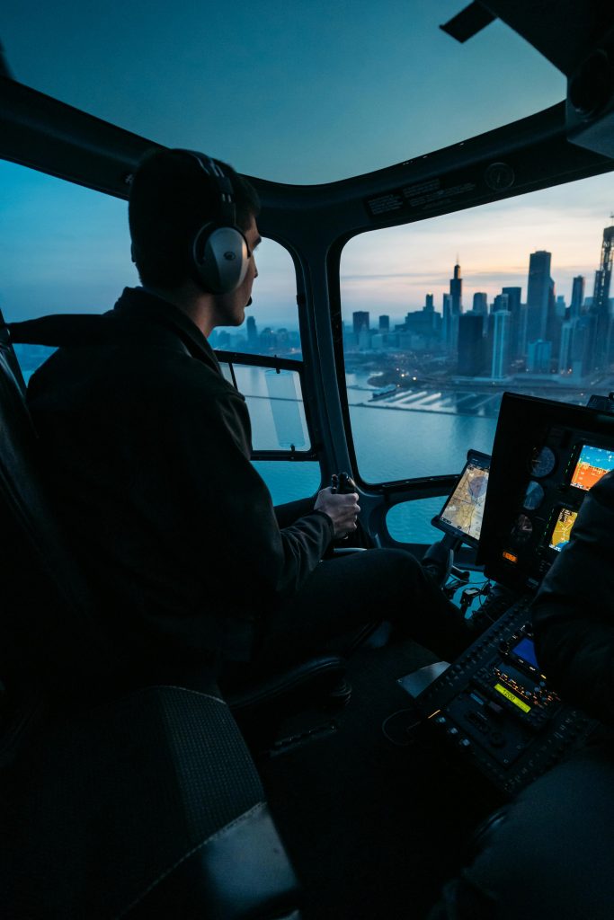 Pilot flying a helicopter over Chicago with skyline view during sunset.